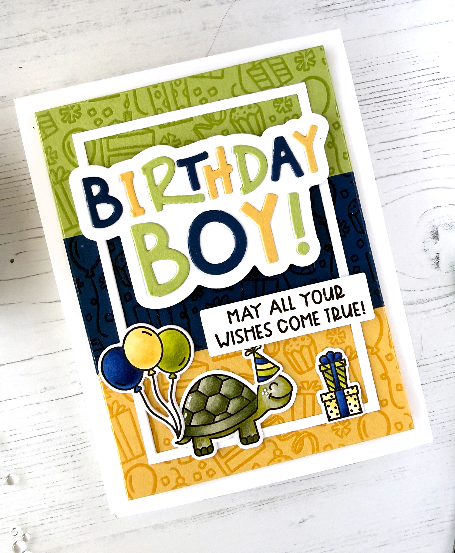A photo of a handmade card with Birthday Boy spelled out in bold bright letters. A turtle carries balloons and birthday presents at the bottom. An additional sentiment reads "may all your dreams come true!"